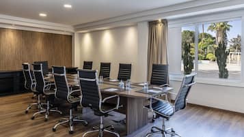 A conference room with a long table, black chairs, and a wooden panel wall.