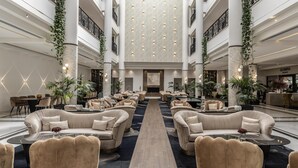 Un lobby amplio con una zona de estar central, techos altos e iluminación decorativa.