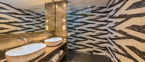 A modern bathroom with two sinks, a large mirror, and a shower area.