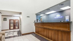Et receptionsområde med et Days Inn skilt, en receptionsdisk, en indtjekningsdisk og et mønstret gulv.