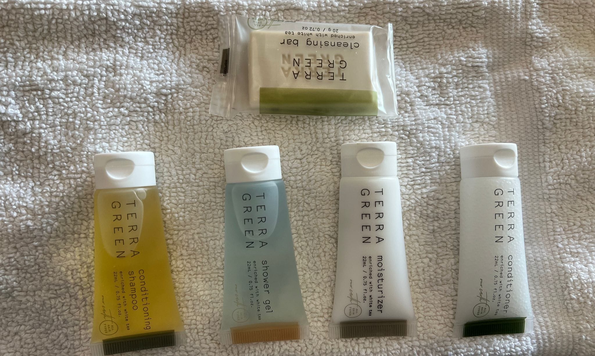 Cinco botellas de productos Terra Green sobre una superficie blanca texturizada.