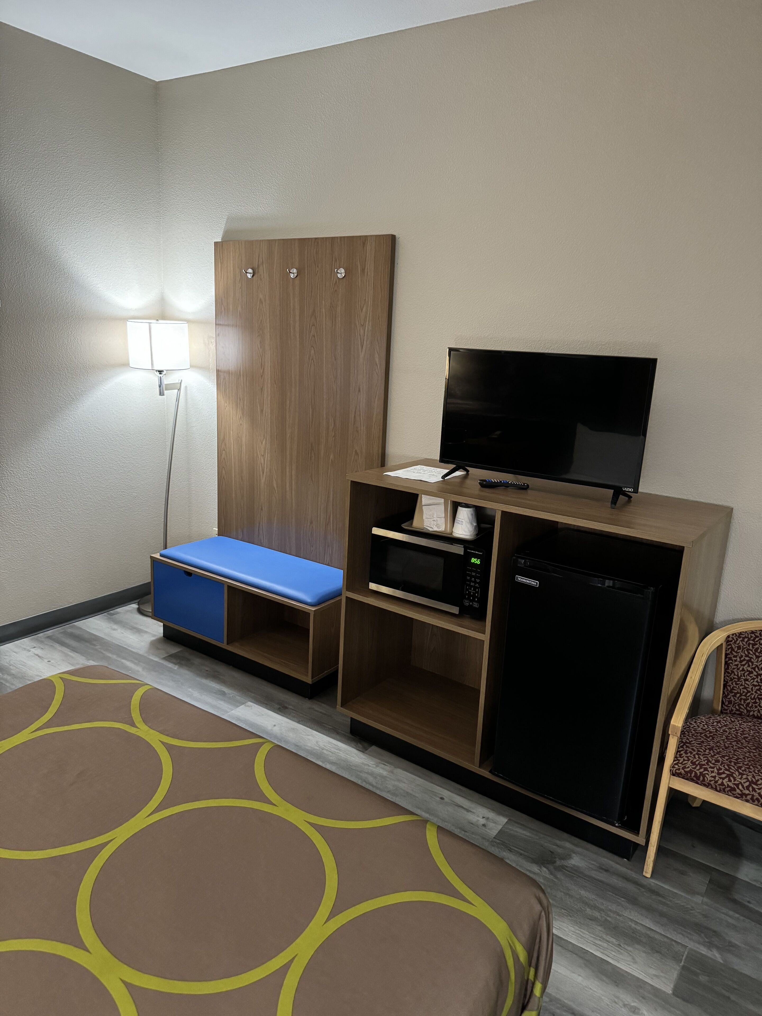 Una habitación de hotel con una cama, un escritorio con televisor, microondas y refrigerador.