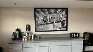 Keittiössä on suuri, kehystetty Arizona-aiheinen taulu, kahvinkeitin, leivänpaahdin ja kahviautomaatti työtasolla.