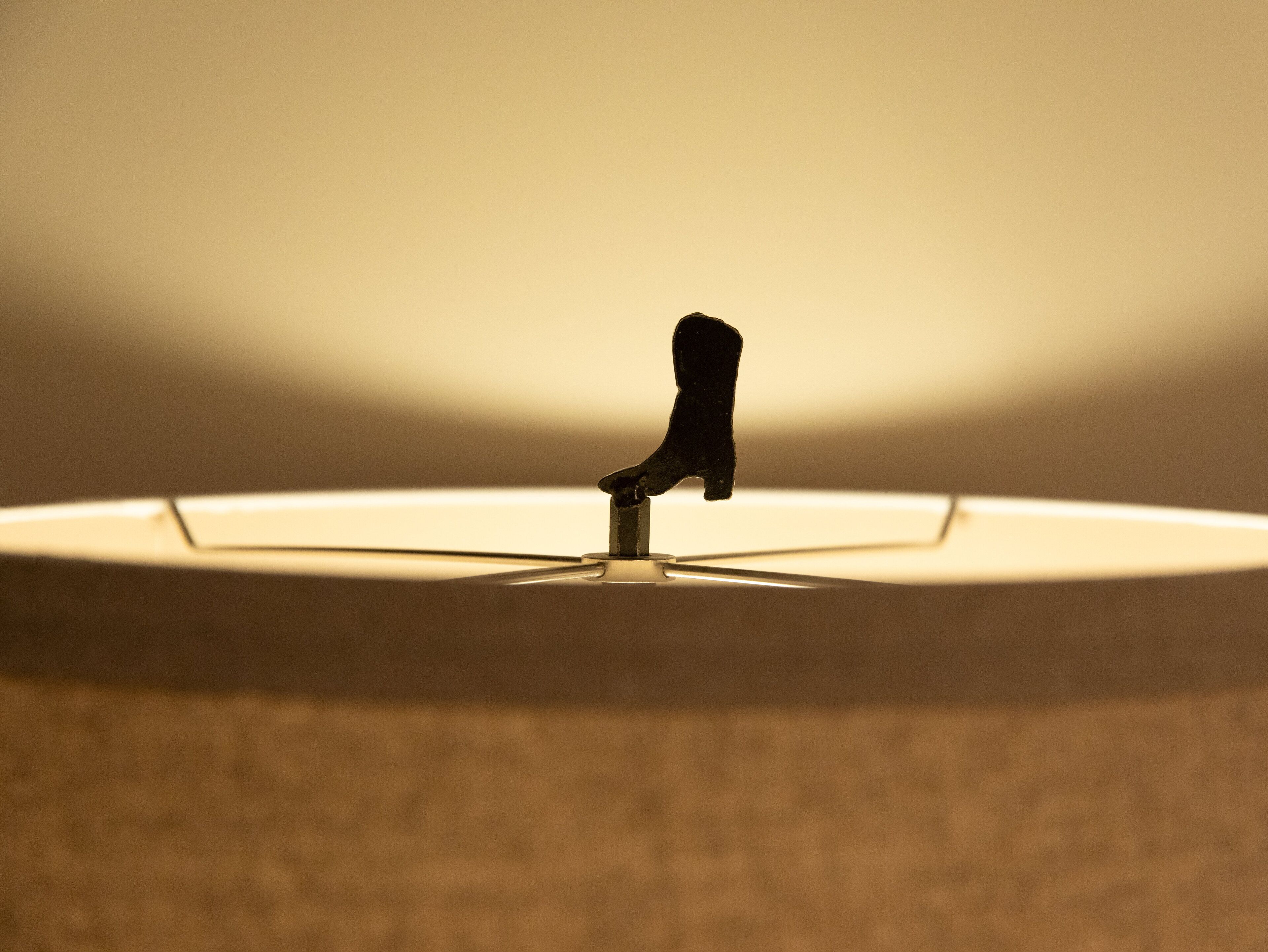 A close-up of a lamp with a single, dark-colored, possibly metallic, handle or knob.