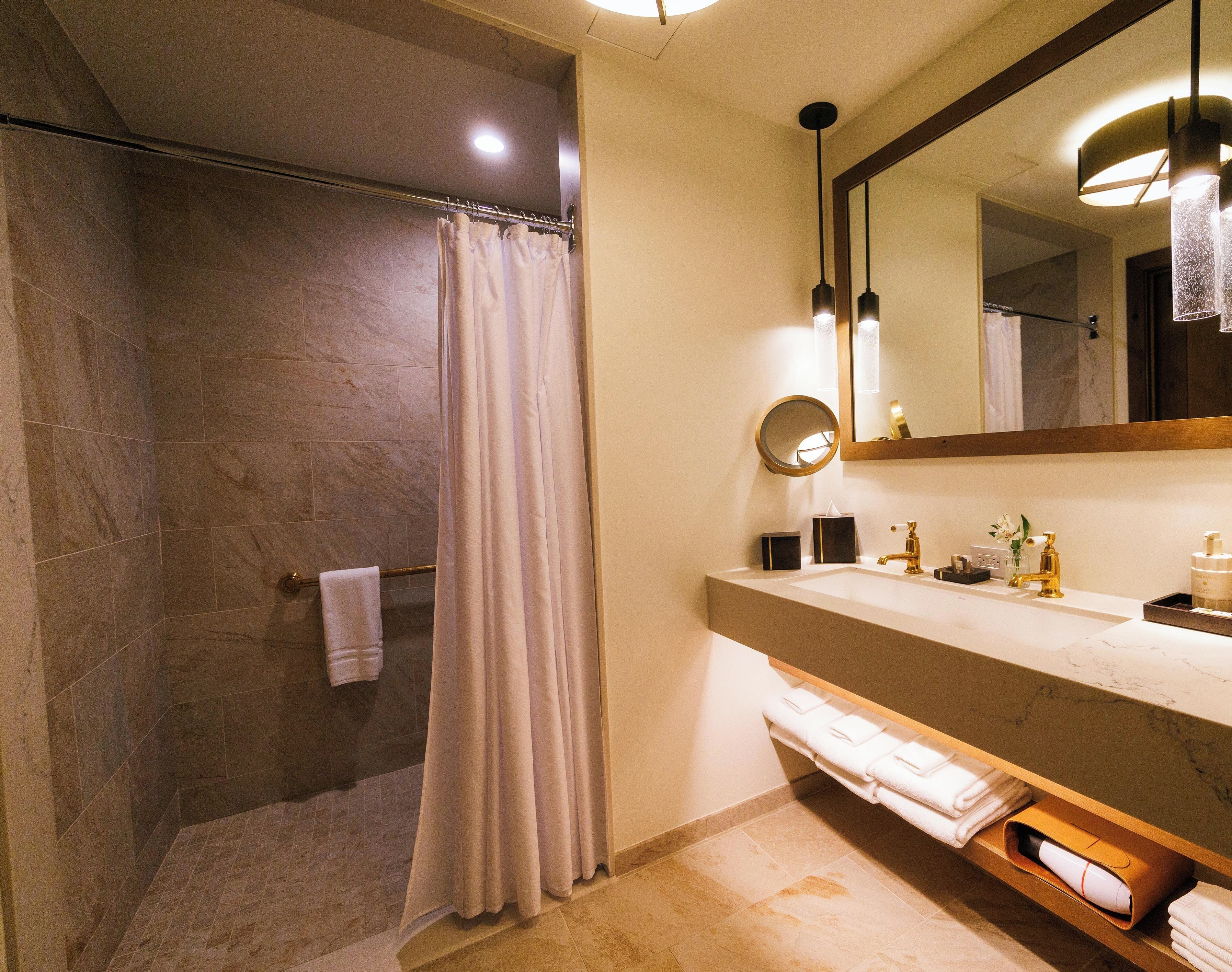 A bathroom with a shower, a sink with a mirror, and a towel rack.