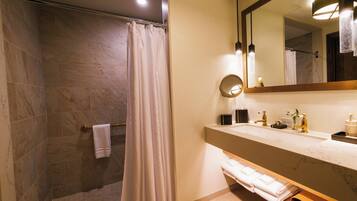 A bathroom with a shower, a sink with a mirror, and a towel rack.