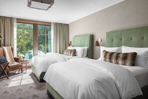 A hotel room with two large beds, a chair, a small table with a vase, and a view of trees through the window. - The Rusty Parrot Lodge and Spa (Jackson)