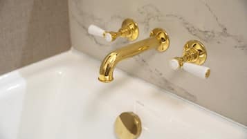 A bathtub with gold fixtures and white handles.