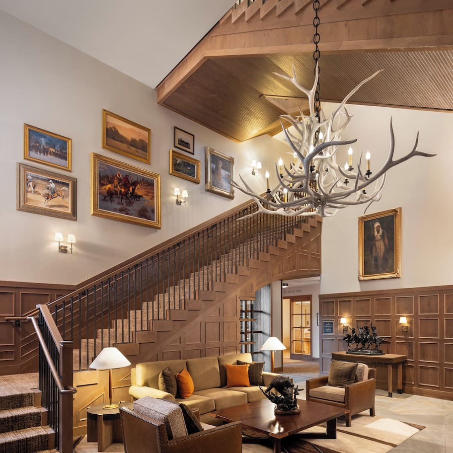 A spacious lobby with a grand staircase, comfortable seating, and a chandelier.