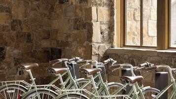 A row of vintage bicycles parked against a stone wall in a room with a large window.