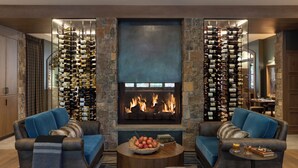 A cozy living room with a fireplace, two sofas, a coffee table with a fruit bowl, and a wine rack. - The Rusty Parrot Lodge and Spa (Jackson)