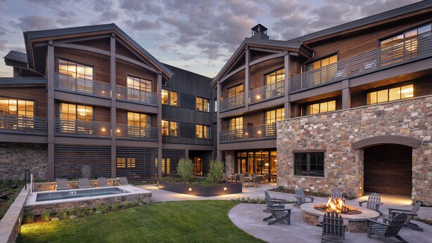 A modern building with multiple balconies, outdoor seating, and a stone fireplace. - The Rusty Parrot Lodge and Spa (Jackson)