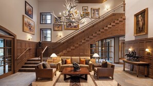A spacious lobby with a grand staircase, a chandelier, and a large sofa set. - The Rusty Parrot Lodge and Spa (Jackson)