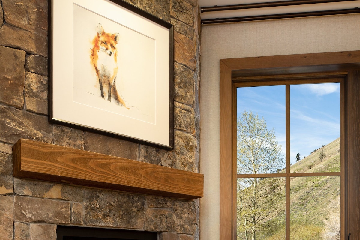 A fireplace with a stone surround, a framed artwork above it, and a leather sofa with a cushion.