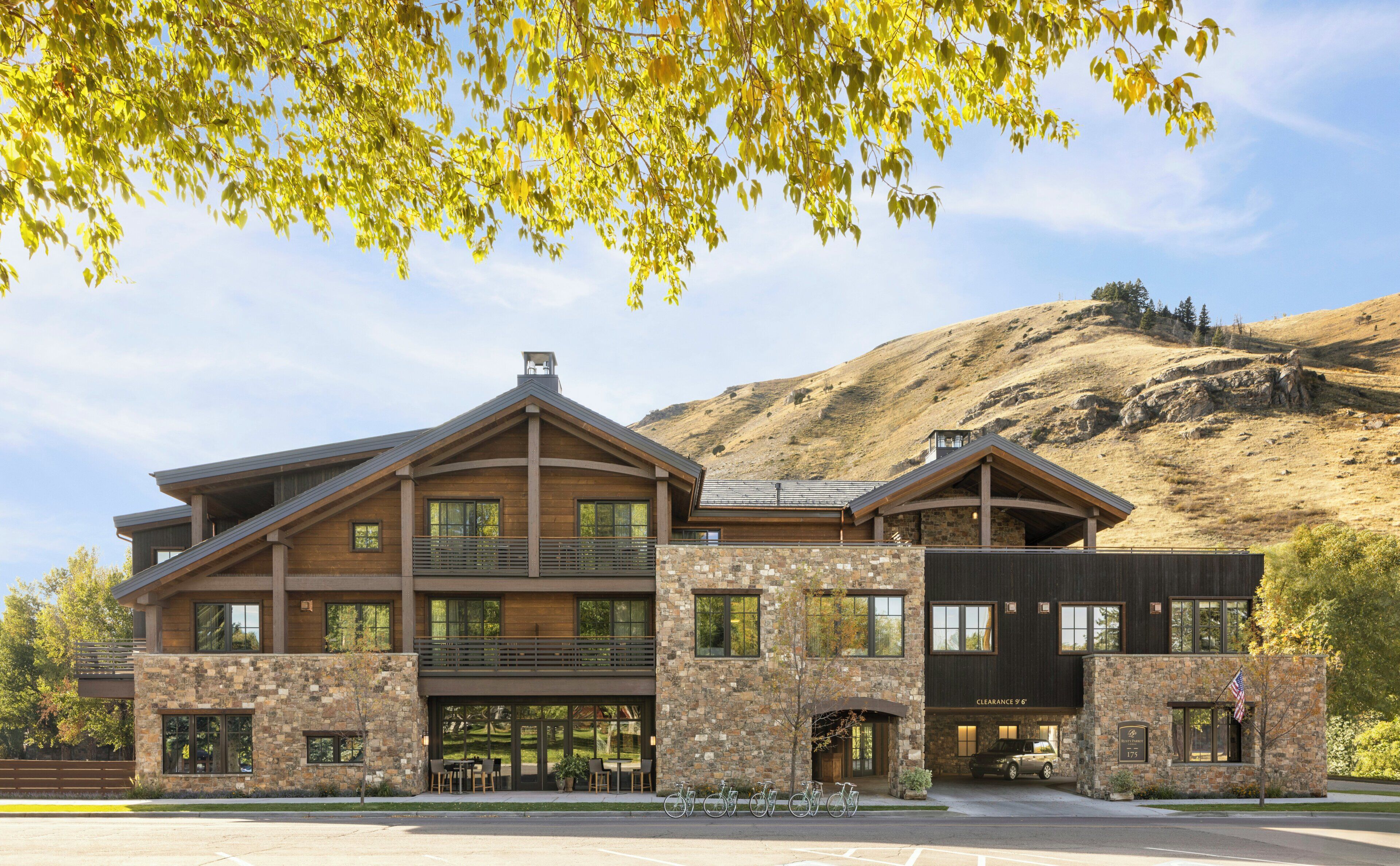 A modern building with a stone facade, large windows, and a covered outdoor seating area.