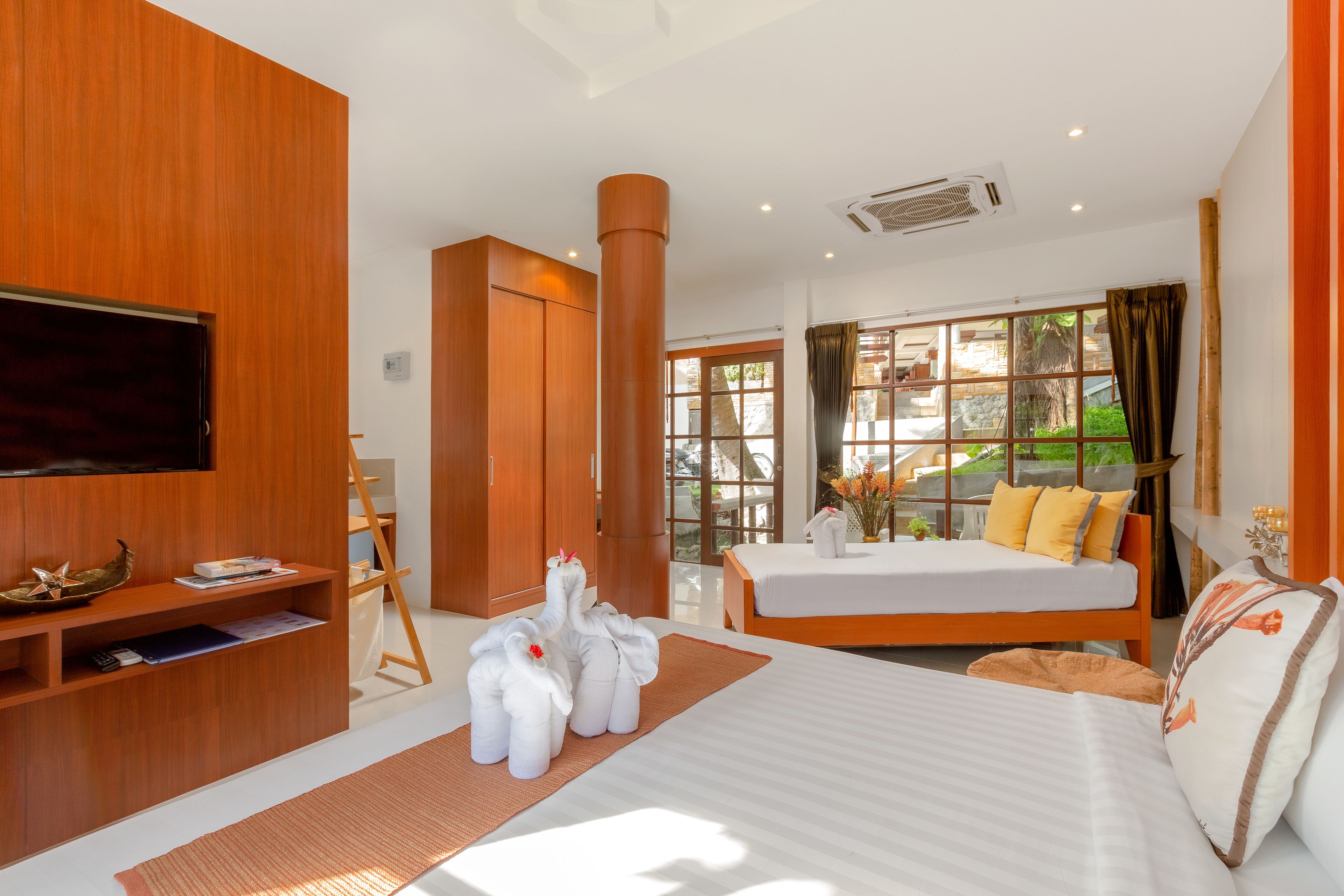A modern hotel room with a large bed, a flat-screen TV, wooden furniture, and a view of the outdoors.