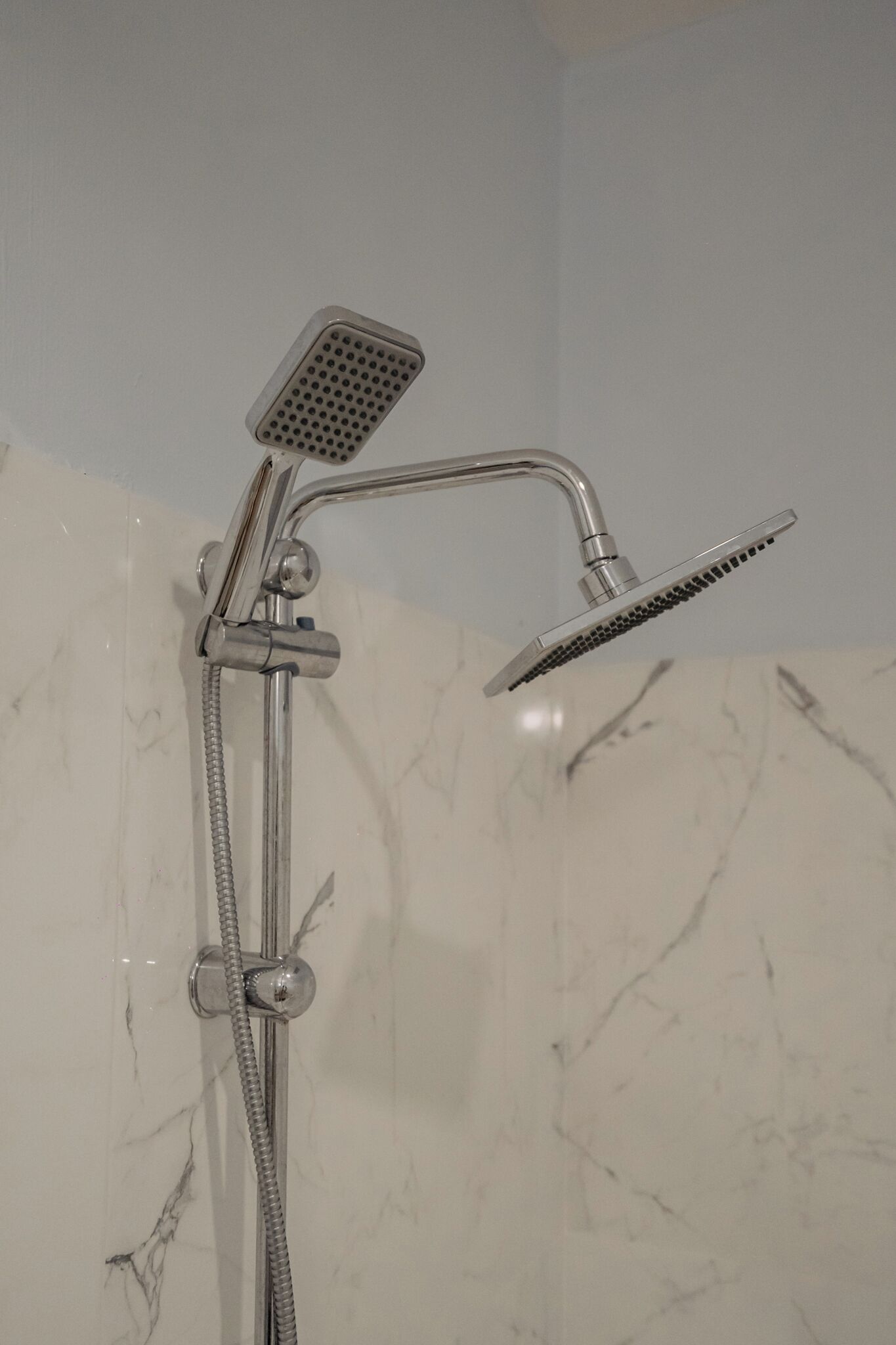 A shower with a handheld showerhead and a fixed showerhead.
