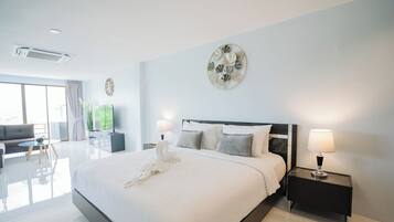 A modern hotel room with a large bed, bedside lamps, a flat-screen TV, and a view of the outdoors.