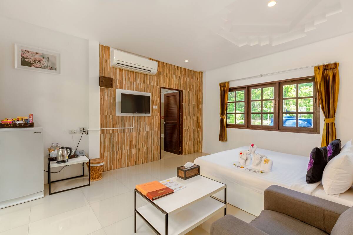 A modern hotel room with a bed, sofa, and a small table.