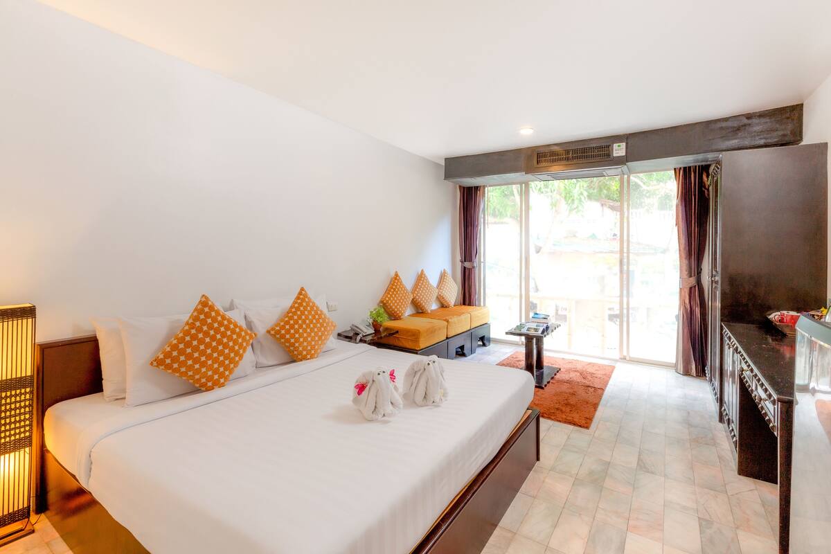 A hotel room with a large bed, a desk, and a view of the outdoors.