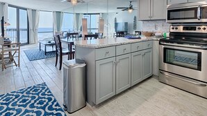 A modern kitchen with a large island, stainless steel appliances, and a view of the ocean. - SunDestin Beach Resort (Destin)