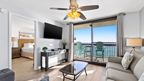 A modern hotel room with a balcony, a flat-screen TV, a dining area, and a sofa. - SunDestin Beach Resort (Destin)