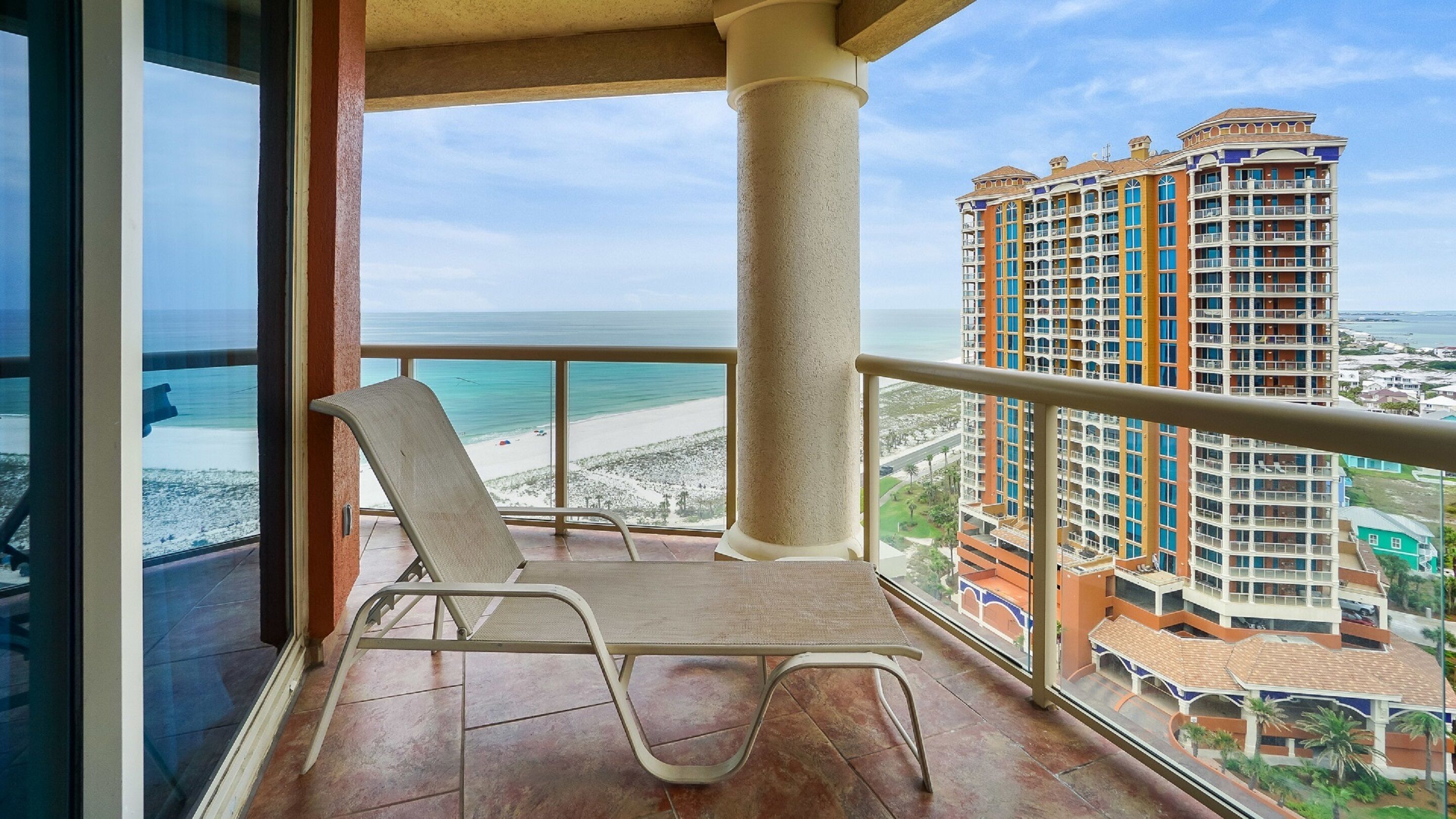 Un balcón con vista a una playa y un edificio de hotel.