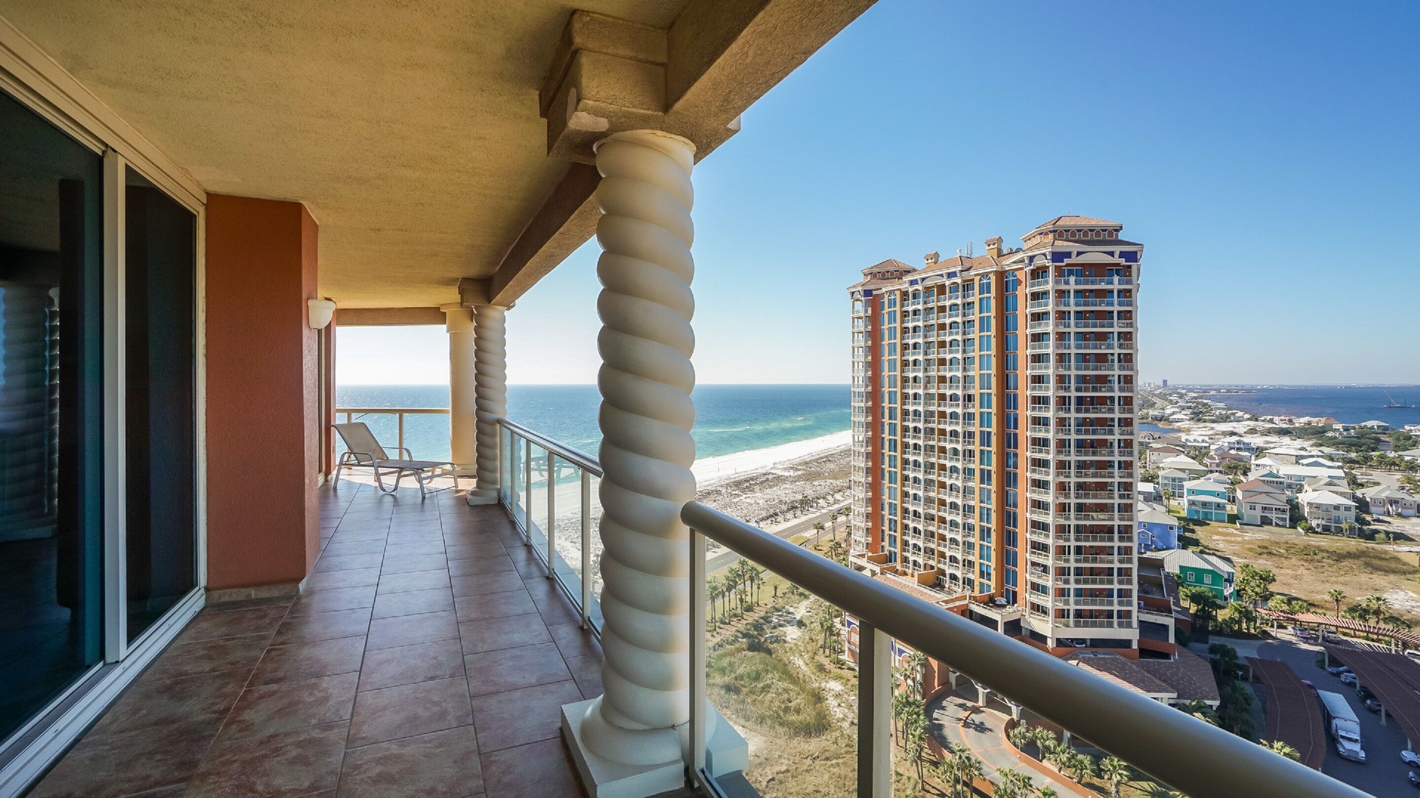 A balcony with a view of the ocean and a tall building in the background.