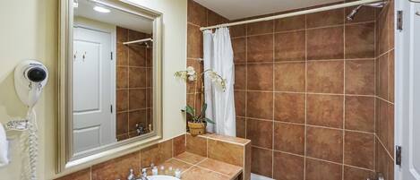 A bathroom with a sink, mirror, and shower.