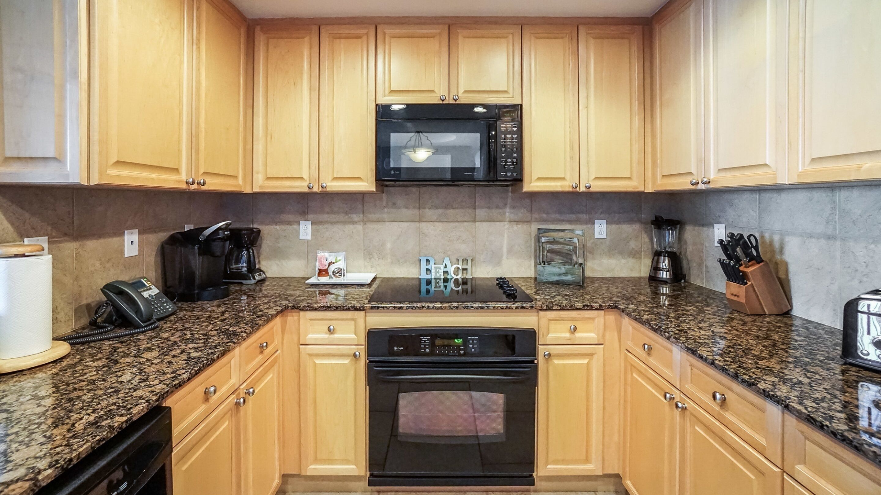 A kitchen with wooden cabinets, a microwave, a coffee maker, a toaster, and a blender.