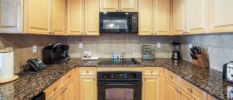 A kitchen with wooden cabinets, a microwave, a coffee maker, a toaster, and a blender.