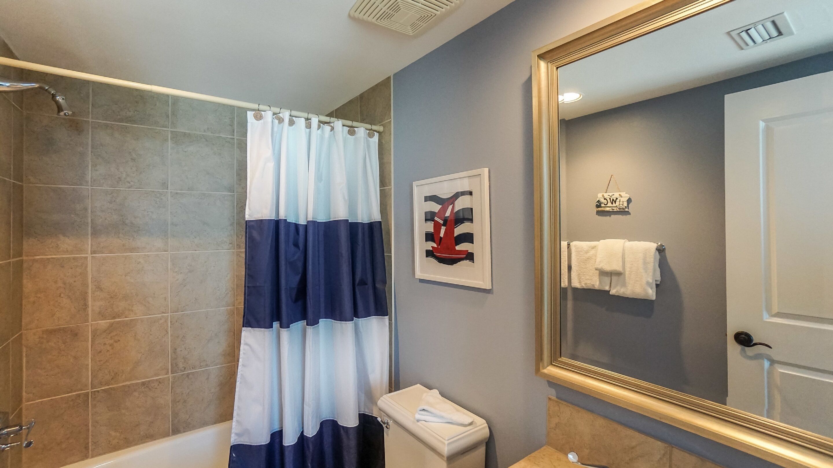 A bathroom with a shower, a toilet, a sink, a mirror, and a towel rack.