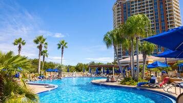 Relax by the resort pool surrounded by palm trees and lounge chairs.