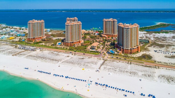 Un complejo turístico con tres edificios altos, una playa y un puerto deportivo.