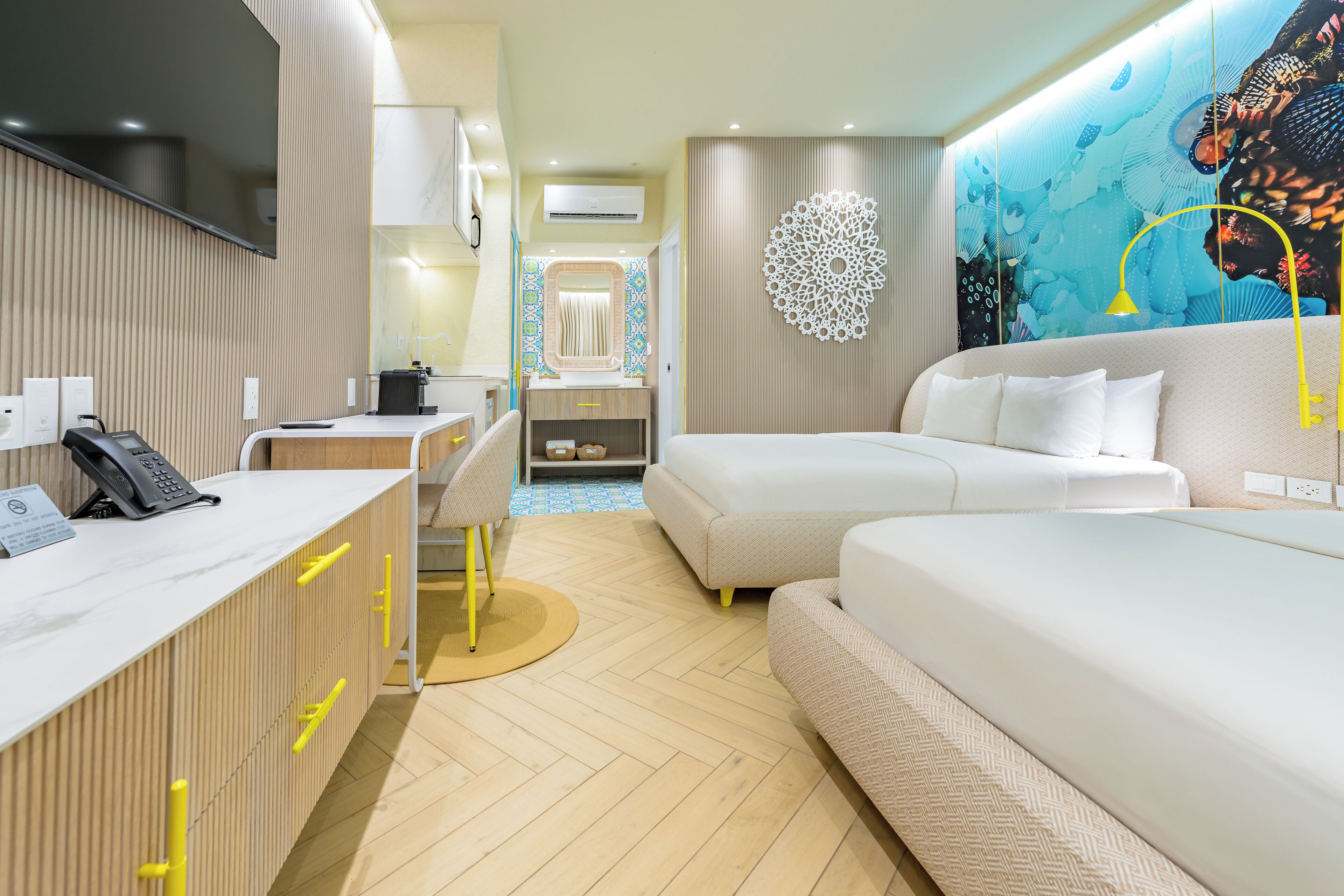Een hotelkamer met een receptiebalie, een bank, een bed, een aan de muur hangend kunstwerk en een vloer met een patroon.