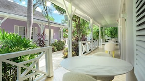 Un espace extérieur abrité, doté d’une balustrade blanche, d’une table ronde et de chaises.