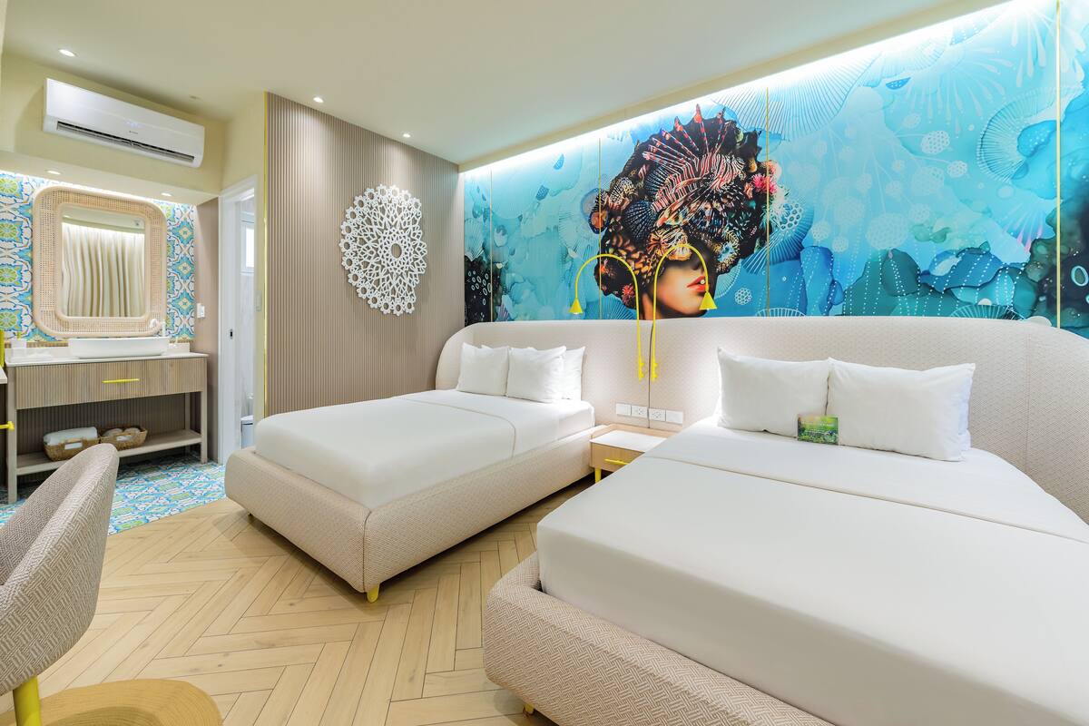 Une chambre d’hôtel avec deux lits, un grand miroir, un mur décoratif et un plancher en bois.