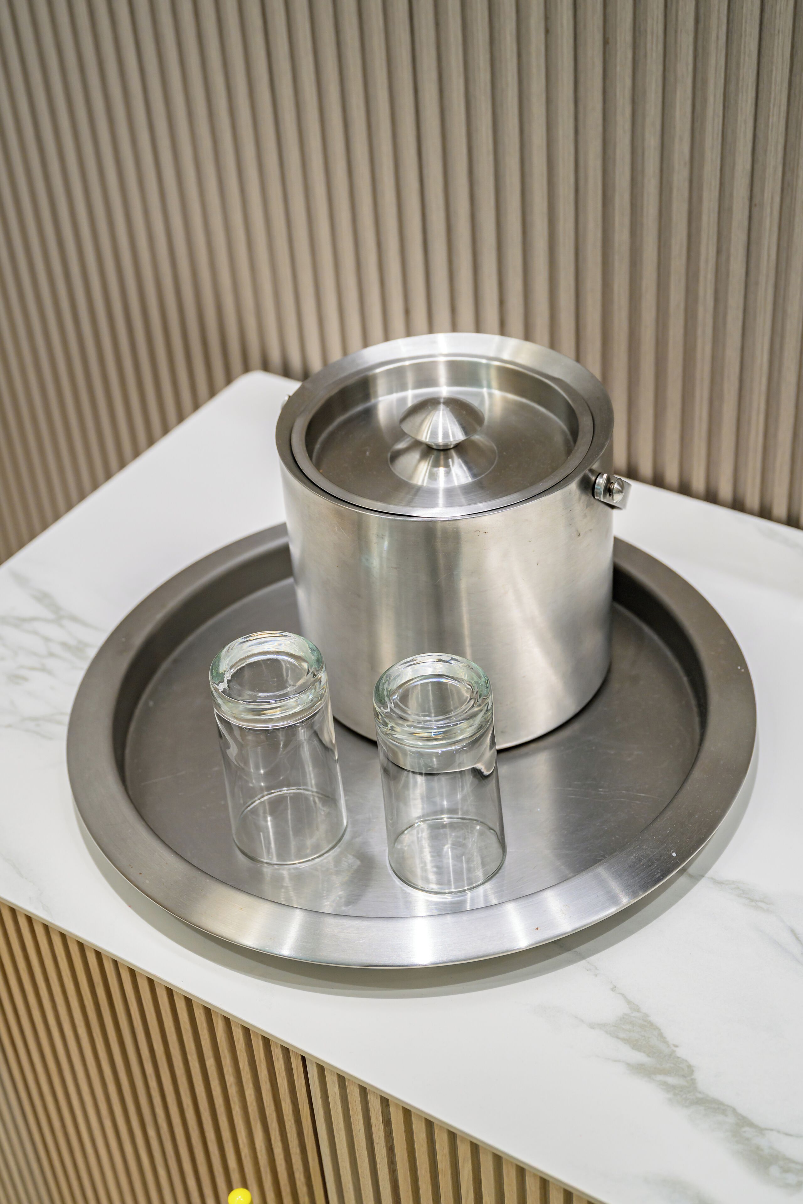 A stainless steel pot on a tray with two shot glasses.