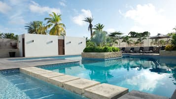 Een buitenzwembad, ligstoelen bij het zwembad