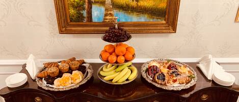 Una mesa de buffet con diversos alimentos, un cuadro en la pared y una mesa de madera oscura.