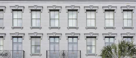 Een hotelgevel in klassieke stijl, met een centrale ingang, meerdere ramen en een decoratief balkon.