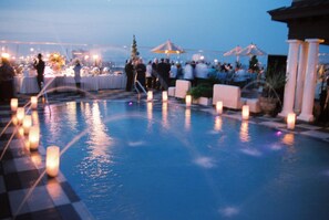 A pool area with a checkered floor, surrounded by lounge chairs and candles. - Market Pavilion Hotel (Charleston)