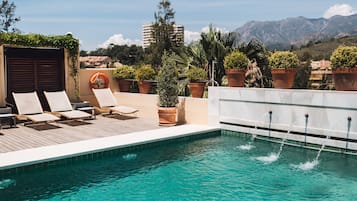 Una piscina al aire libre, sombrillas, sillones reclinables de piscina