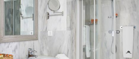 Un baño moderno con lavamanos de mármol, un espejo grande, ducha con cerramiento de vidrio y un inodoro.