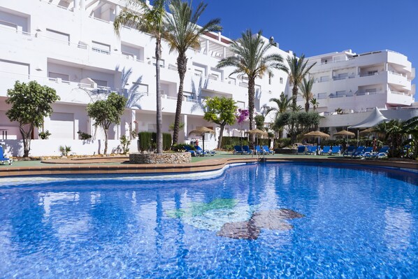 Una piscina al aire libre de temporada, sombrillas