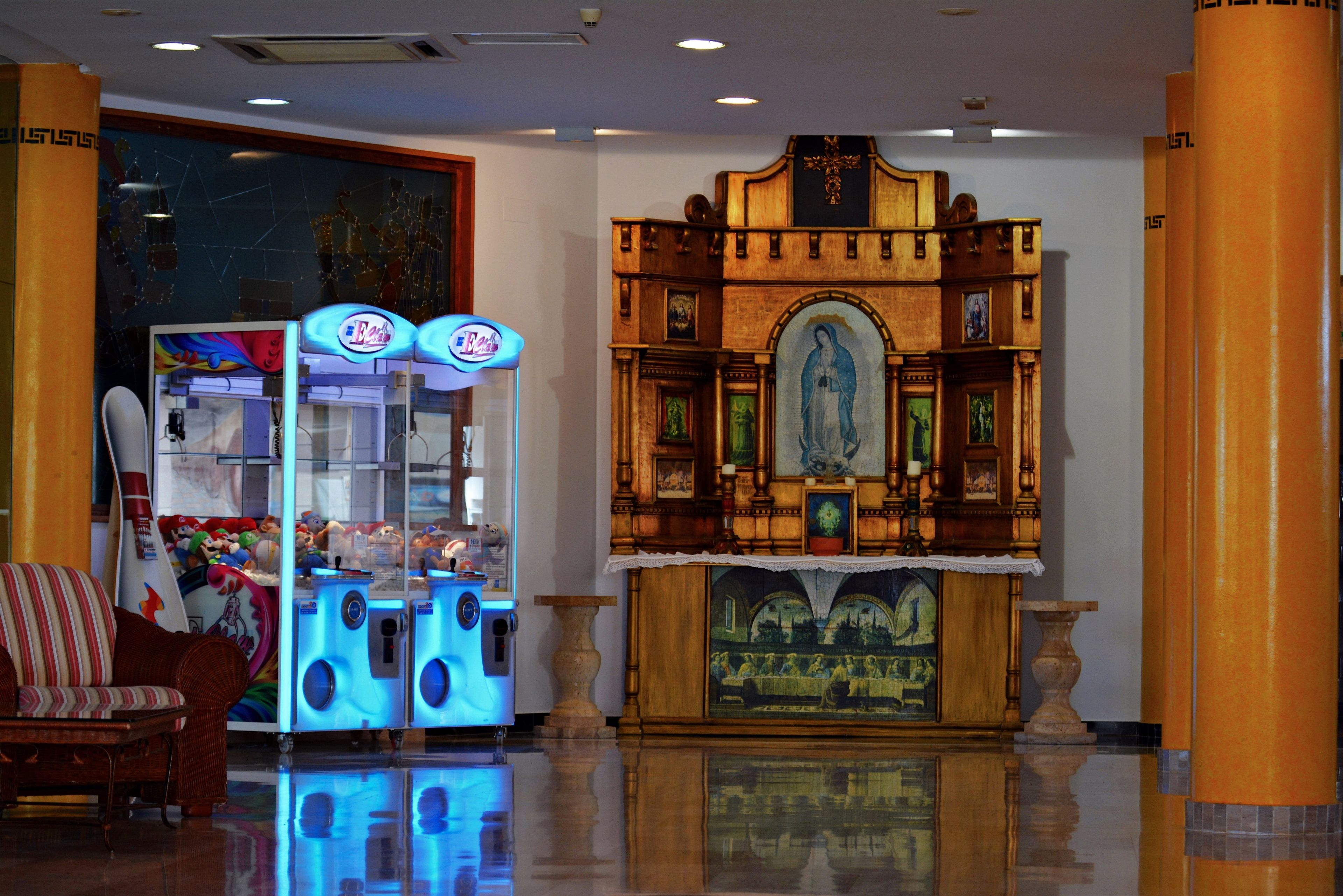 Un vestíbulo con un altar de madera, una máquina expendedora y un sillón acolchado.