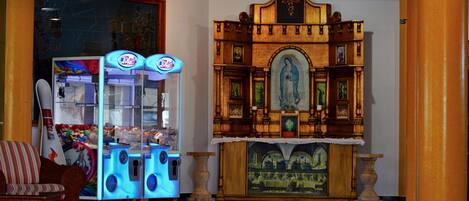 Un vestíbulo con un altar de madera, una máquina expendedora y un sillón acolchado.