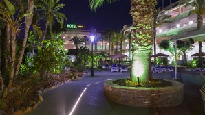 A hotel with a well-lit entrance, palm trees, and outdoor seating areas. - Apartamentos Mexico (Vera)