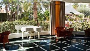 A hotel room with a checkered floor, a view of a pool area, and a window with curtains. - Apartamentos Mexico (Vera)