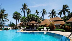 Una piscina con sillones de descanso y palmeras.